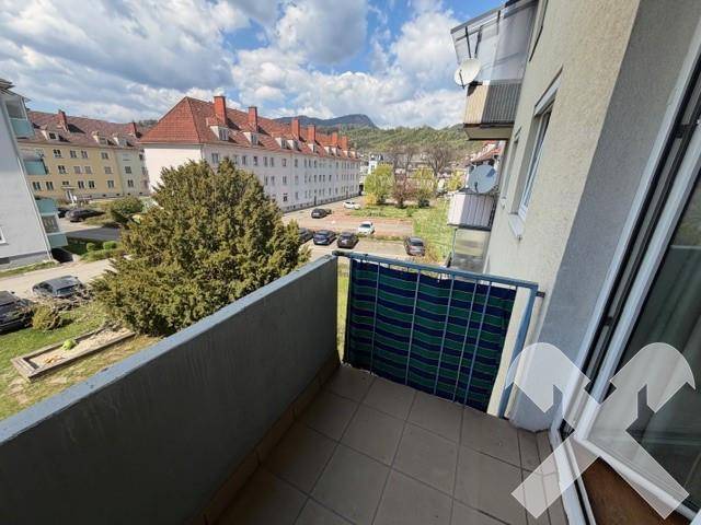 Balkon mit Blick auf eine Wohnsiedlung, Bäume und geparkte Autos.