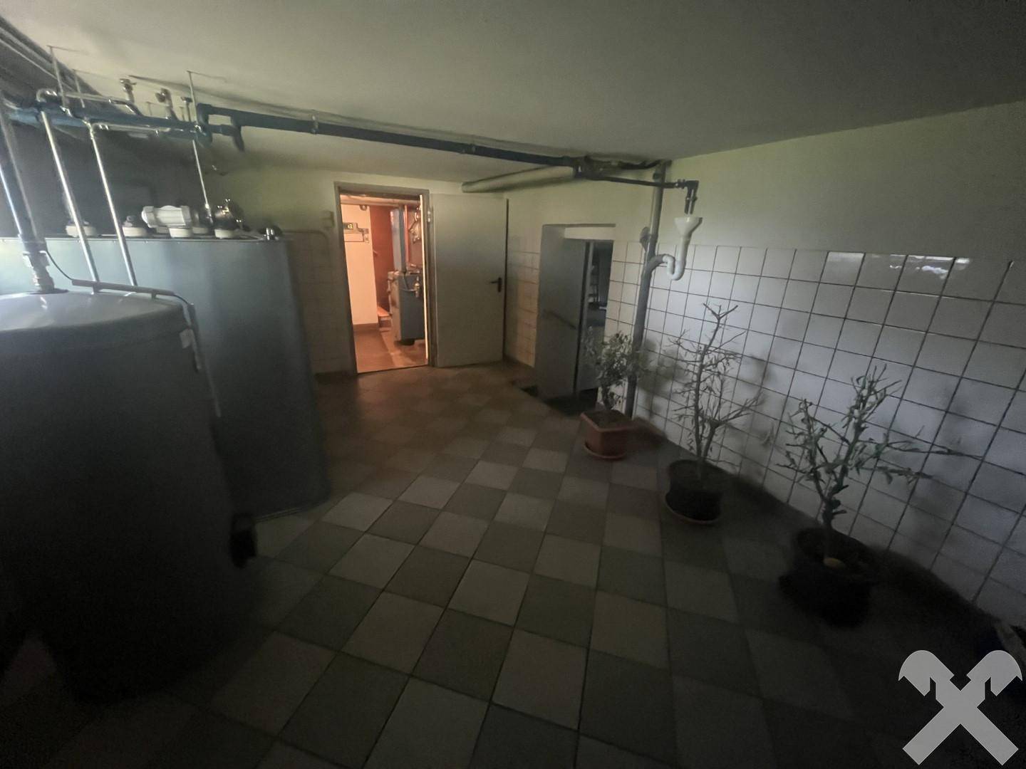 Kellerbereich mit großen Speichertanks und gefliestem Boden, bietet Zugang zu weiteren Räumen.