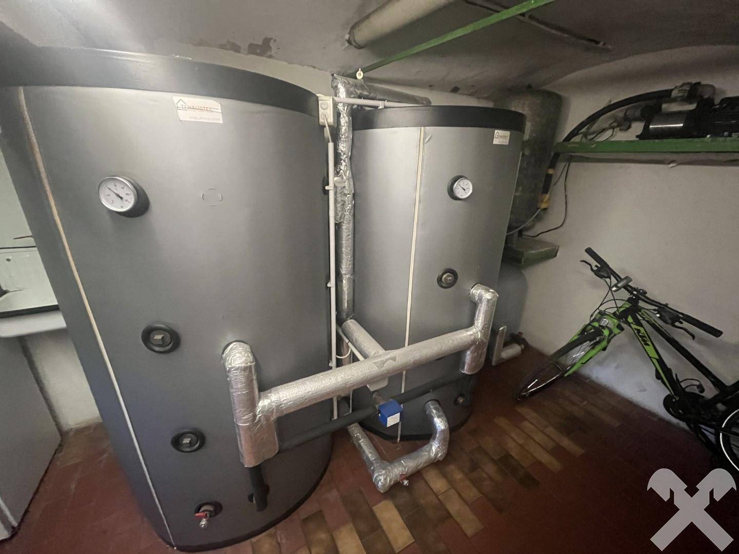 Kellerraum mit großen Warmwasserspeichern und einem Fahrrad, genutzt als Abstellfläche.