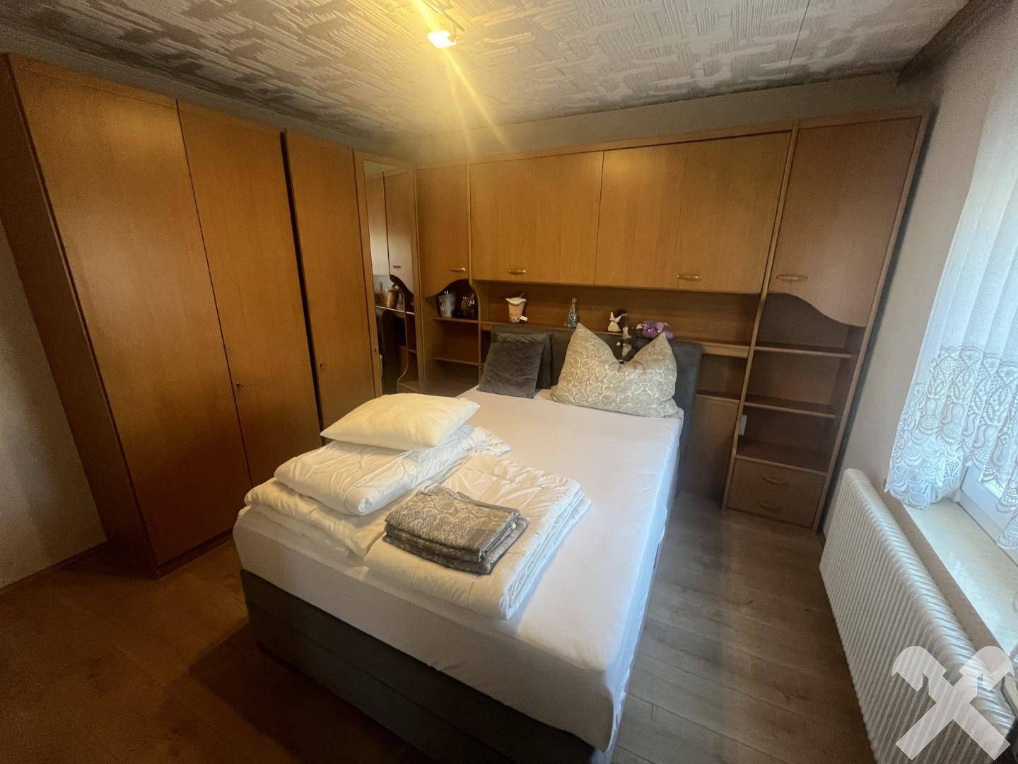 Geräumiges Schlafzimmer mit umfangreichen Holz-Einbauschränken und einem bequemen Doppelbett.