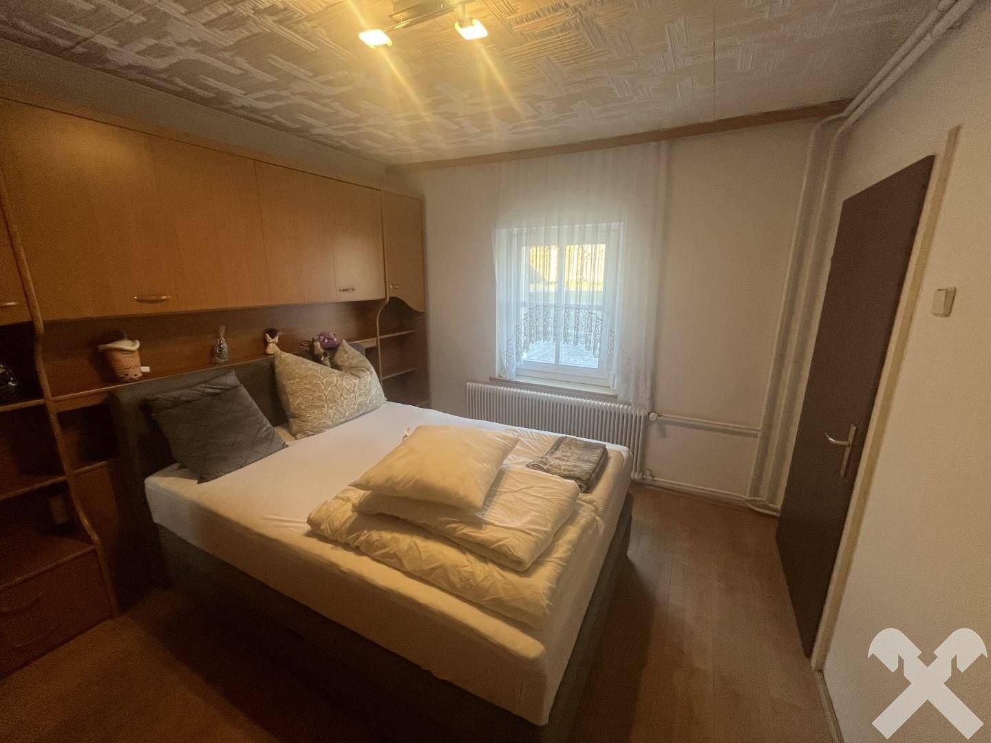 Schlafzimmer mit Doppelbett, integrierten Holzschränken und einem Fenster, das für natürliches Licht sorgt.