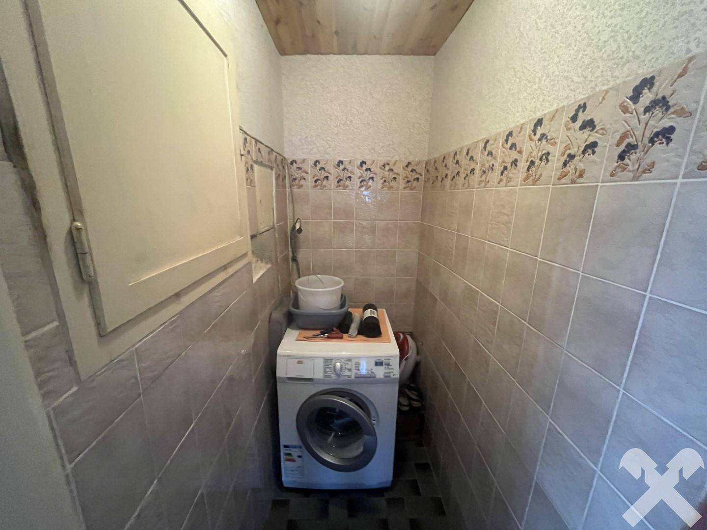 Hauswirtschaftsraum mit Waschmaschine und gefliesten Wänden, ideal für die Wäschepflege.