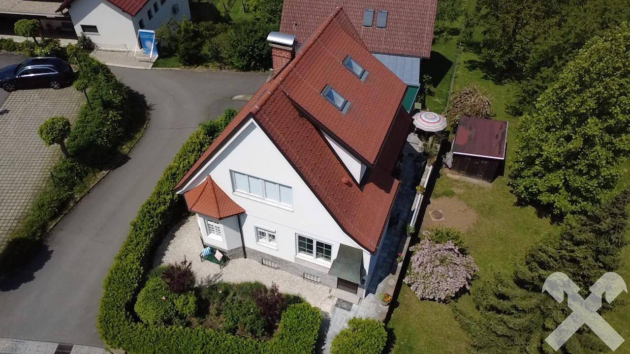 Luftaufnahme des Hauses mit rotem Ziegeldach, großem Garten und weitem Blick über die Landschaft.