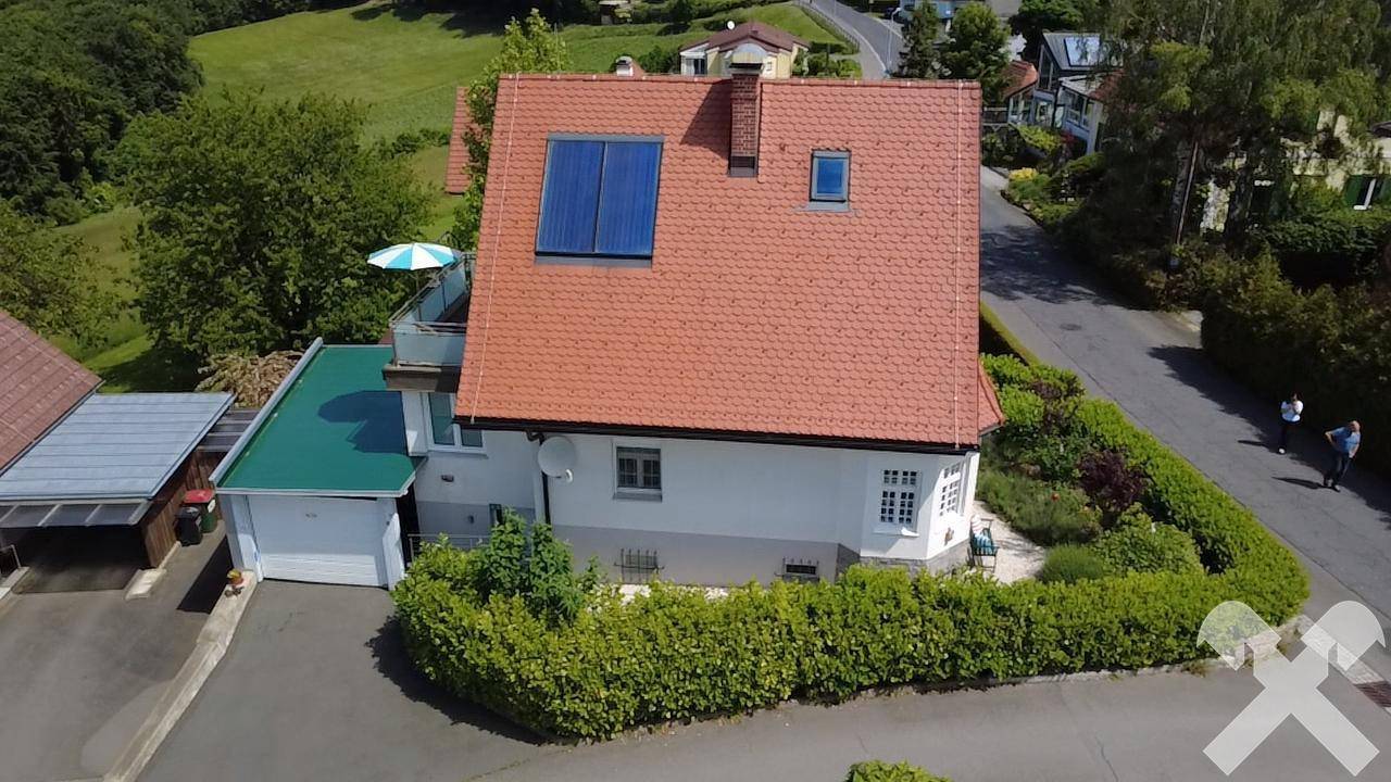 Luftaufnahme des Hauses mit Solaranlage auf dem Dach, umgeben von Garten und Nachbarschaft.