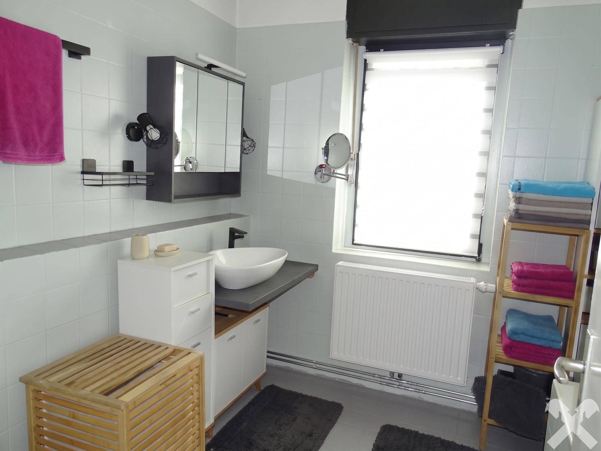 Modernes Badezimmer mit Waschbecken, Spiegelschrank und Fenster für Tageslicht.