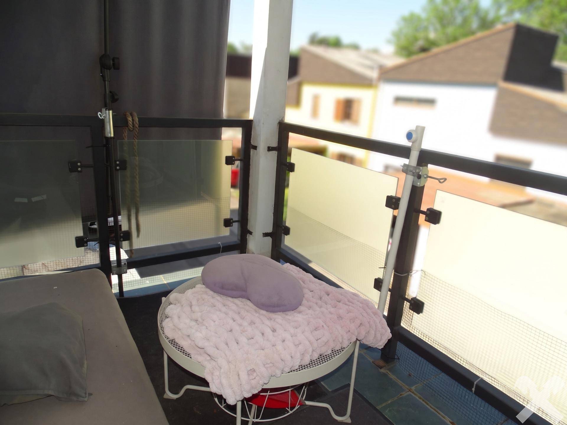 Kleiner Balkon mit gemütlicher Decke und Kissen, ideal für entspannte Momente im Freien.