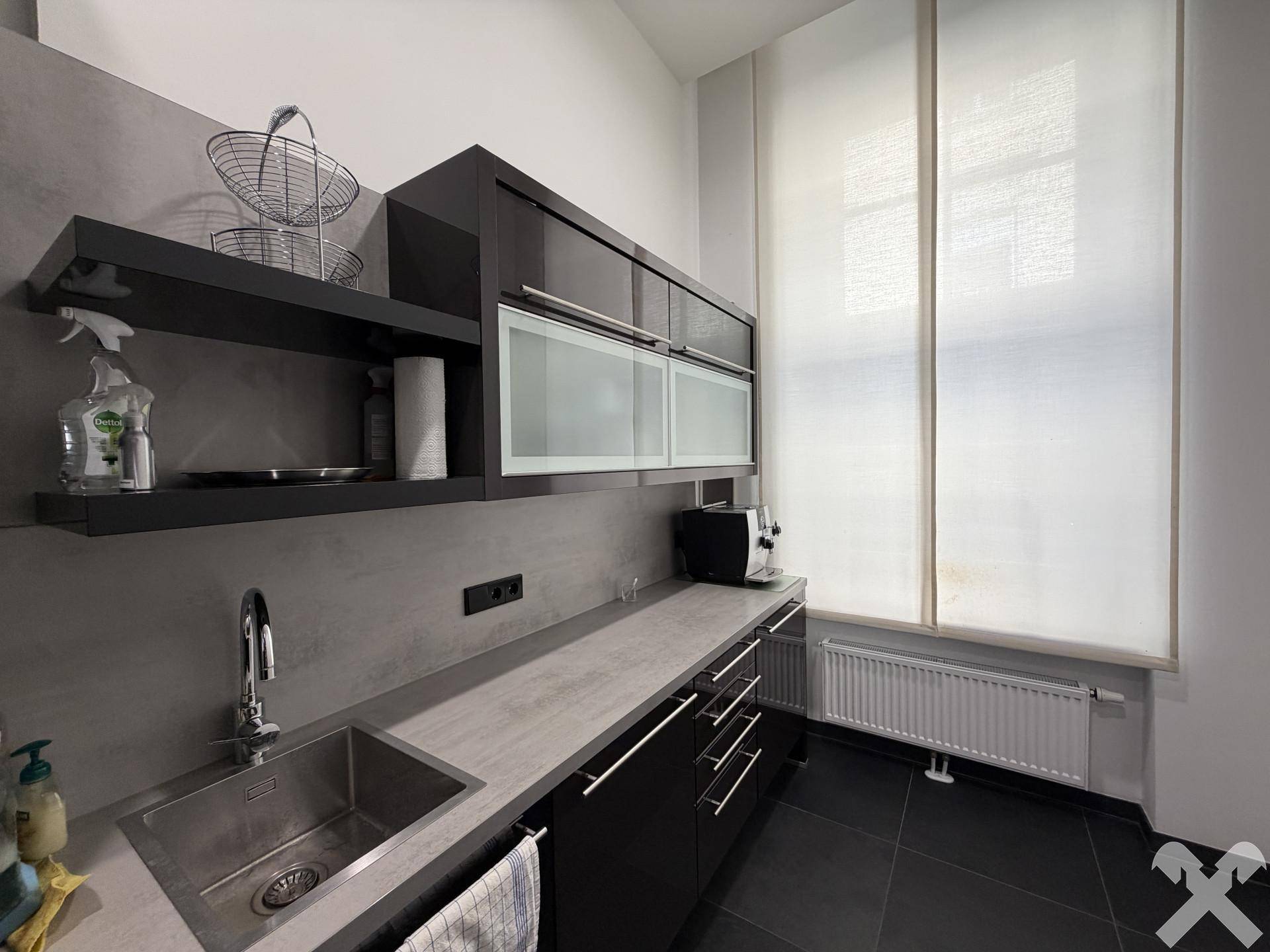 Kleine moderne Küchenzeile mit dunklen Schränken, Spüle und Fenster.