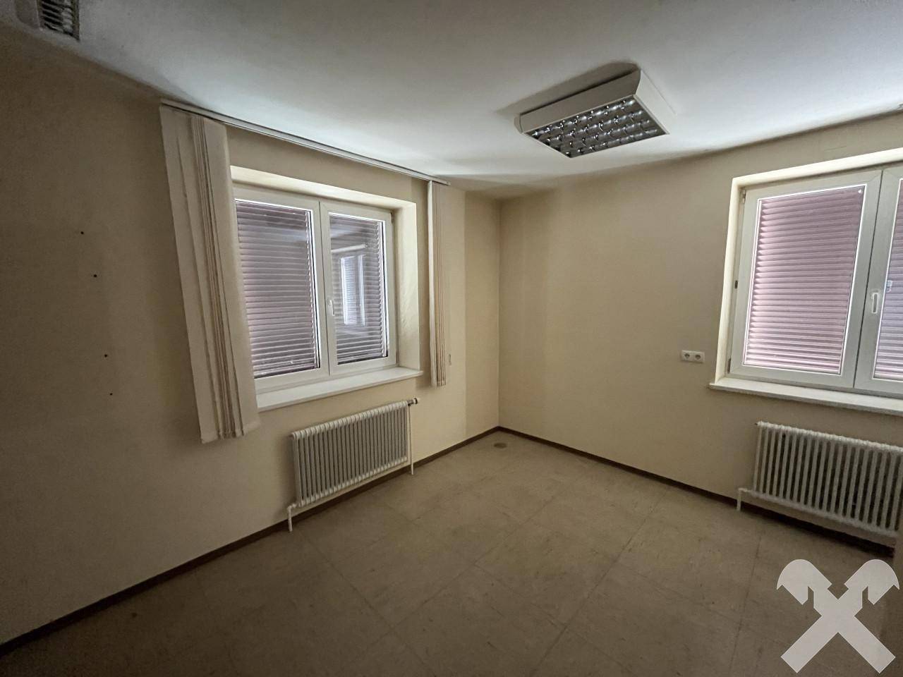 Heller Raum mit zwei Fenstern, Heizkörpern und Fliesenboden, ideal als Büro.