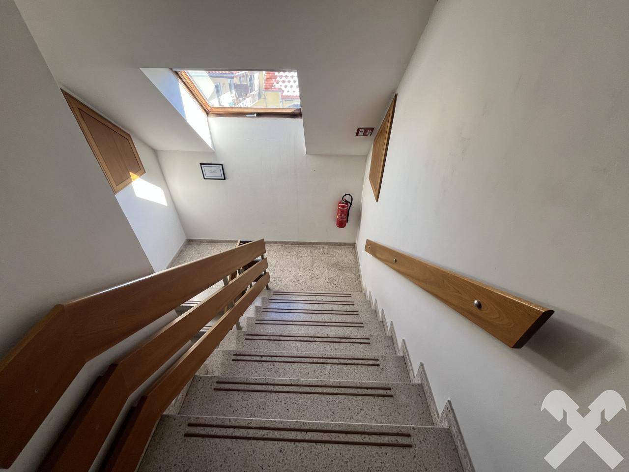 Treppenhaus mit Holzgeländer und Dachfenster, sorgt für natürliches Licht.