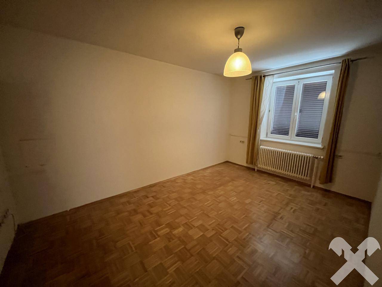 Geräumiges Schlafzimmer mit Parkettboden, Fenster und Deckenleuchte, hell und einladend.