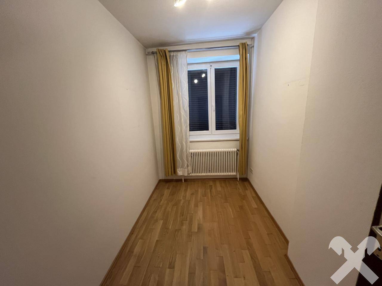 Kleines Zimmer mit Holzparkettboden, Fenster und Heizkörper, ideal als Schlafzimmer.