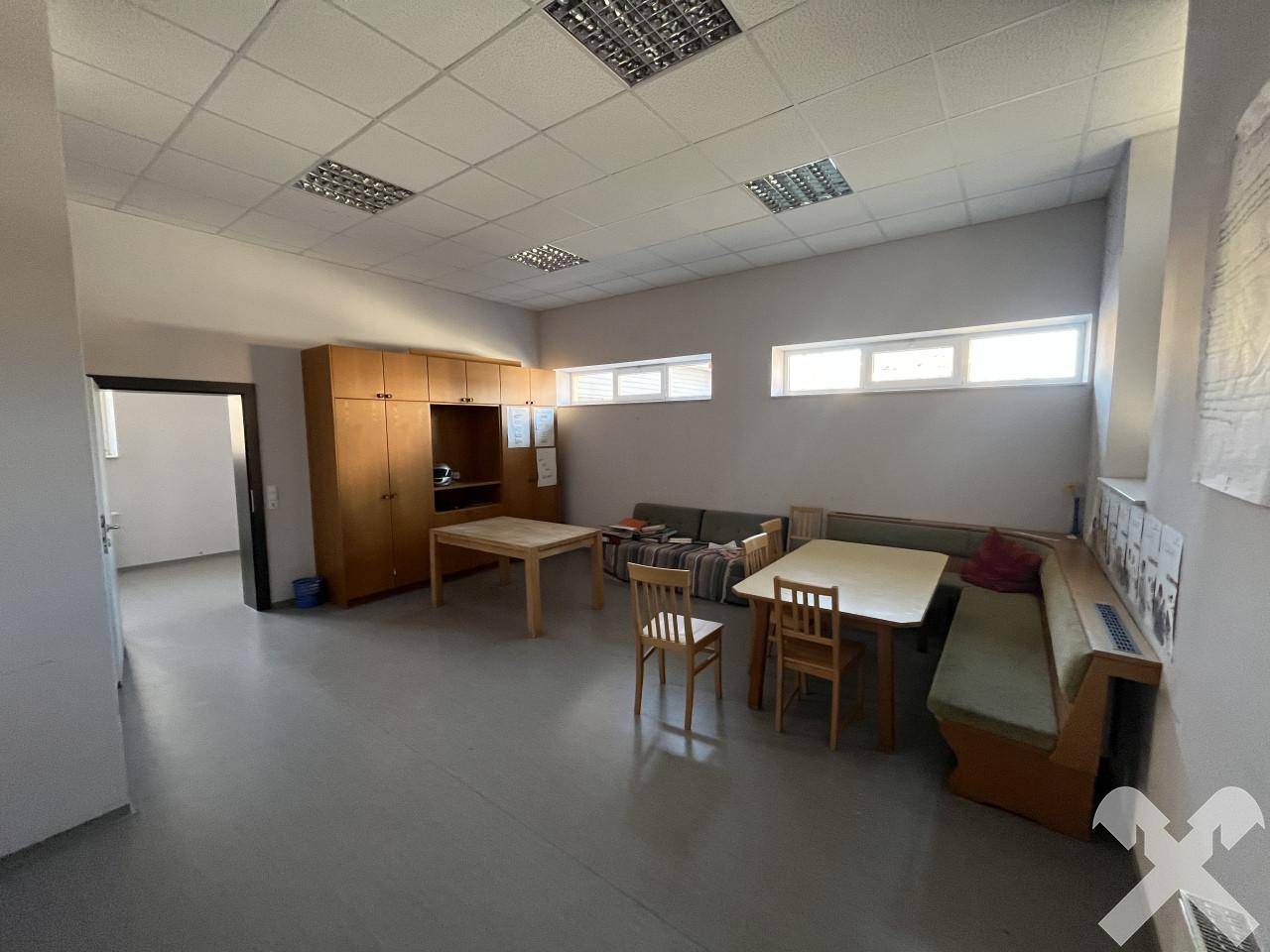 Geräumiger Gemeinschaftsraum mit Holztischen, Bänken und Schränken, gut beleuchtet.