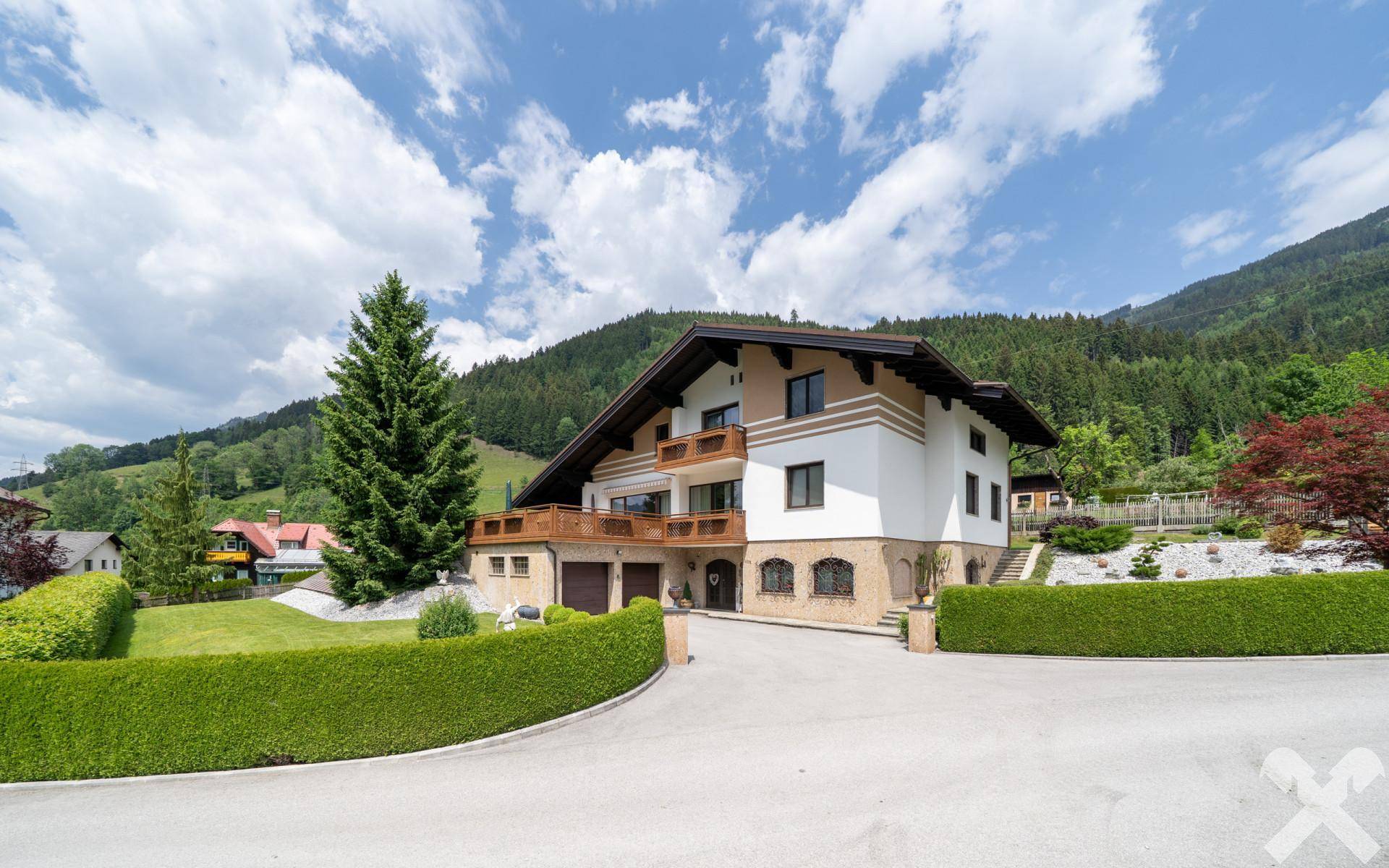 Attraktives Einfamilienhaus im alpinen Stil mit Doppelgarage und gepflegter Auffahrt, umgeben von Bergen.