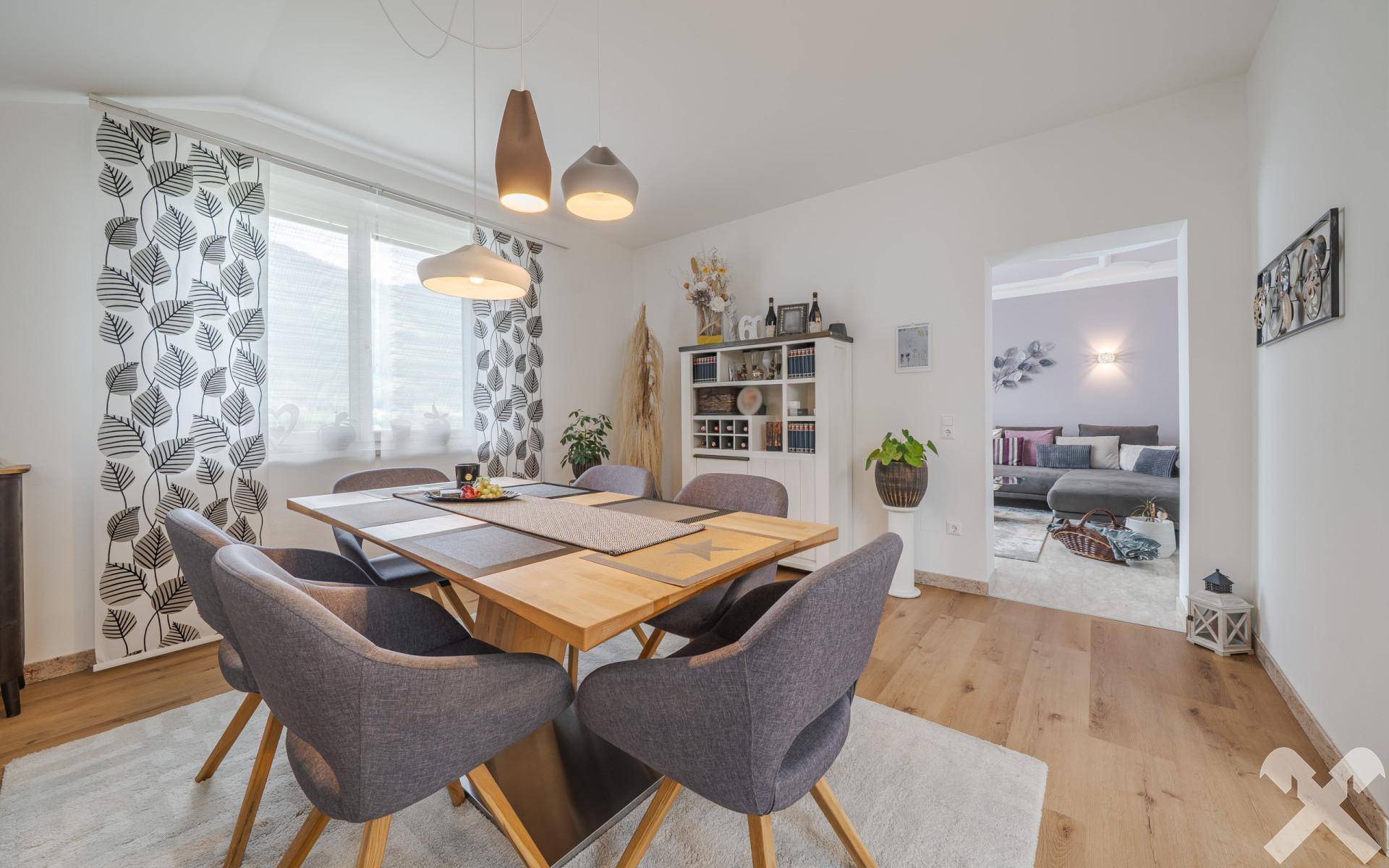 Heller Essbereich mit Holztisch und modernen Stühlen, offen zum Wohnzimmer und mit Blick ins Grüne.