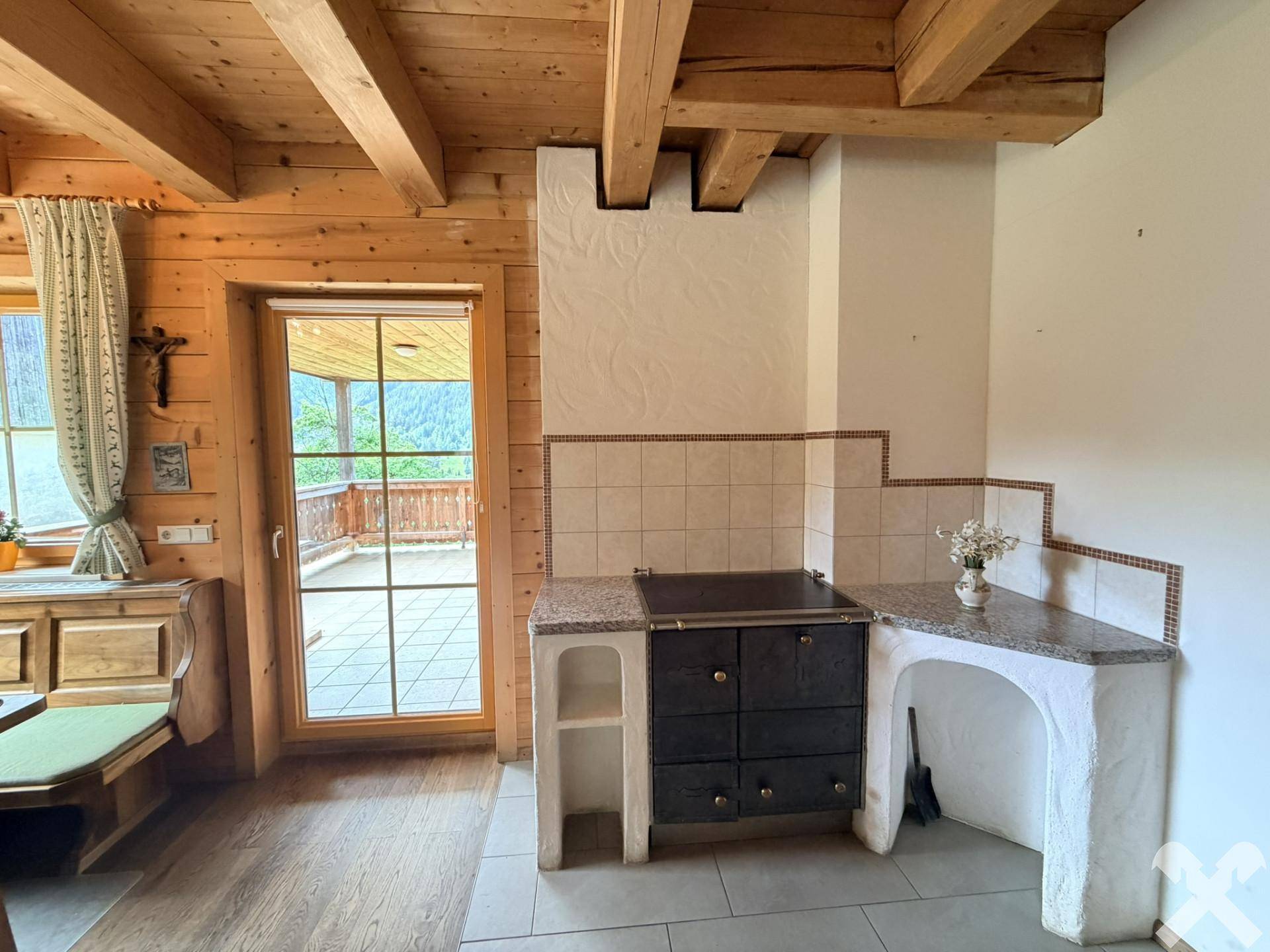 Traditioneller Holzofen mit Granitplatte in der Küche, ergänzt durch einen Zugang zum Balkon.