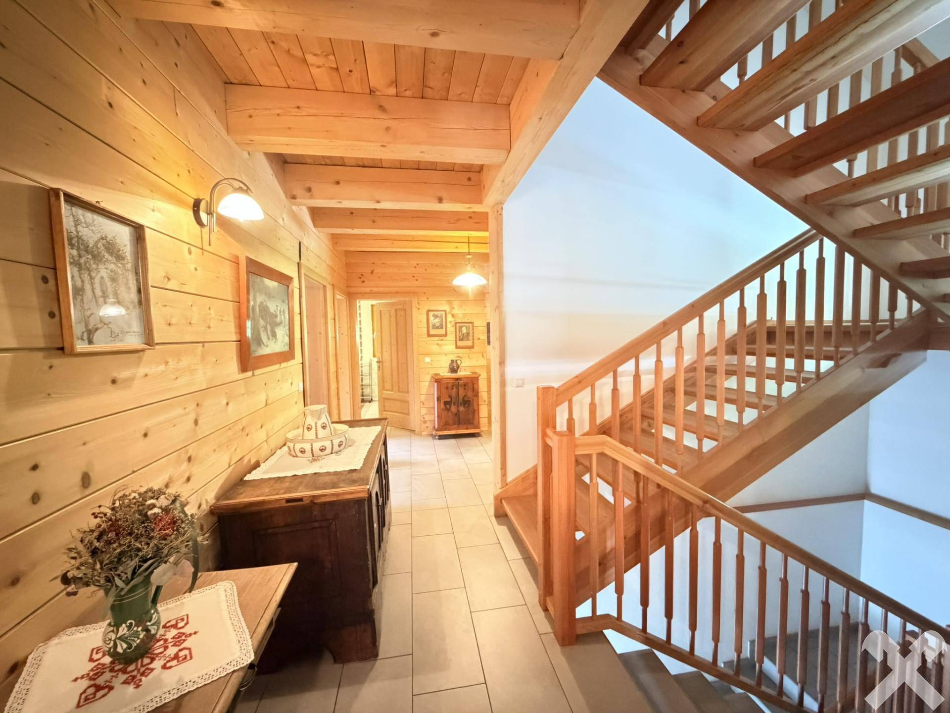 Heller Flur mit Holztreppe und Holzbalkendecke, verbindet die verschiedenen Ebenen des Hauses.