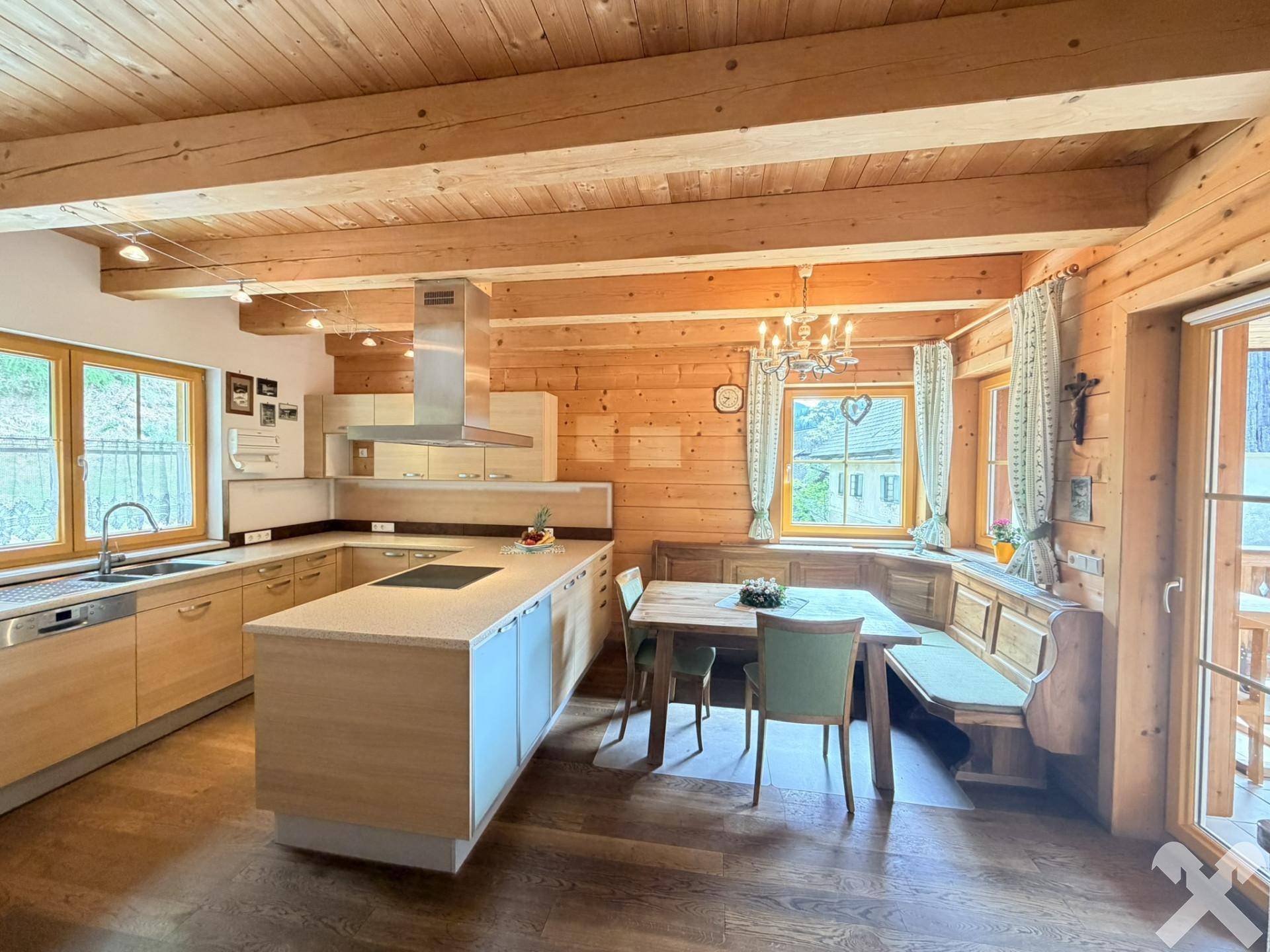Geräumige Holzküche mit Essbereich, Kücheninsel und Holzbalkendecke, ideal für gesellige Runden.