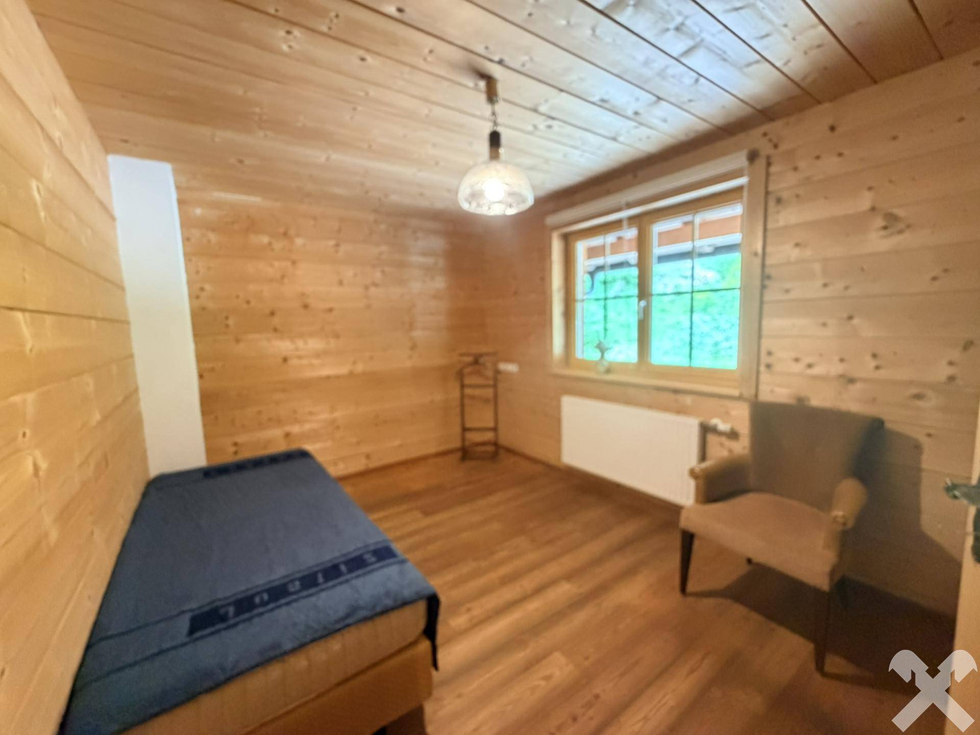 Schlafzimmer mit Holzwänden und -decke, bietet eine ruhige und natürliche Atmosphäre.