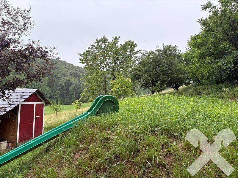 Hanglage im Garten mit Rutsche und Blick auf die umliegende Natur.