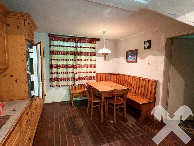 Gemütlicher Essbereich in der rustikalen Küche mit Holztisch, Stühlen und einer traditionellen Eckbank.