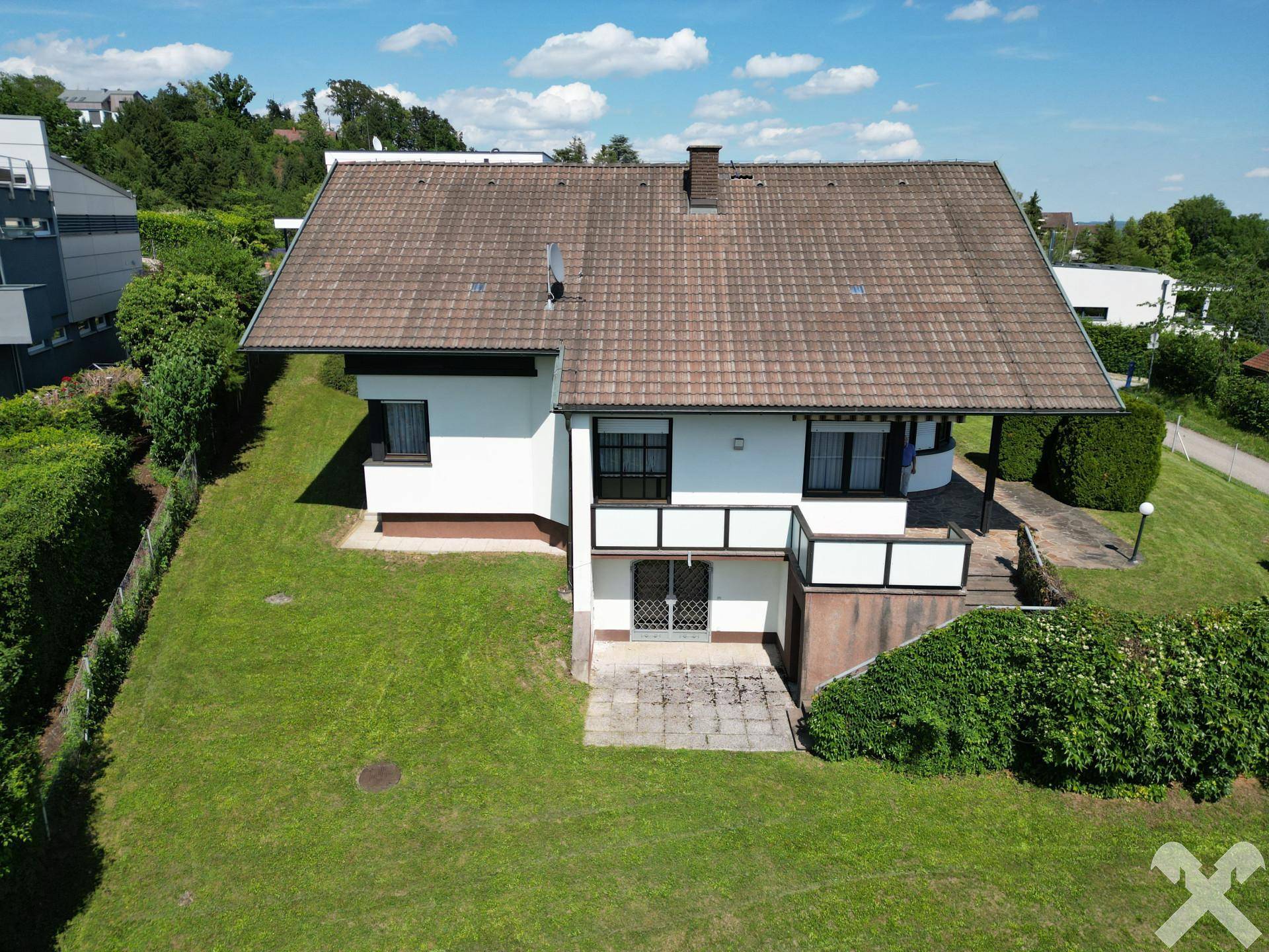 Rückansicht des Hauses mit Terrasse im Erdgeschoss und großem, gepflegtem Rasenbereich.
