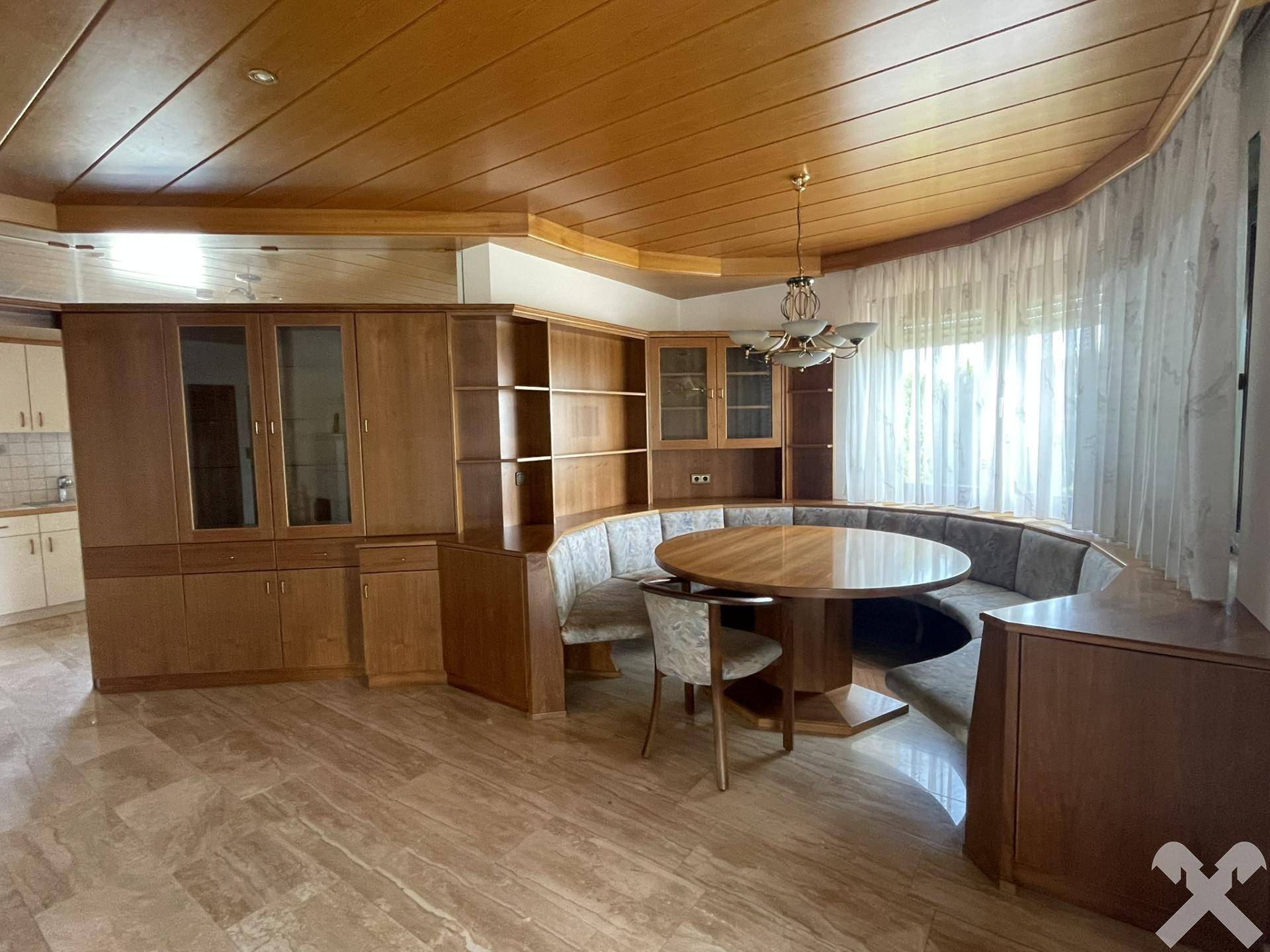 Gemütlicher Essbereich mit runder Holztafel, eingebauten Sitzbänken und passenden Holzmöbeln.