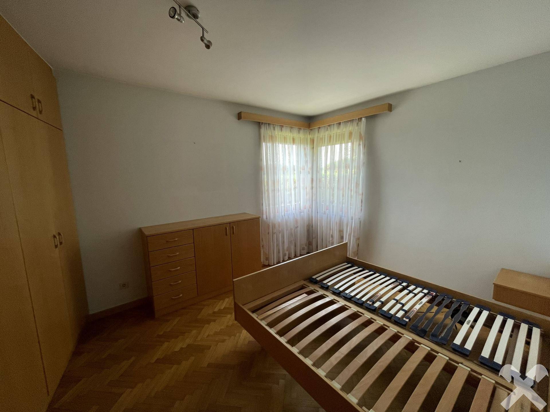 Schlafzimmer mit Parkettboden, hellen Wänden und einfacher Holzmöblierung, bereit zur Einrichtung.
