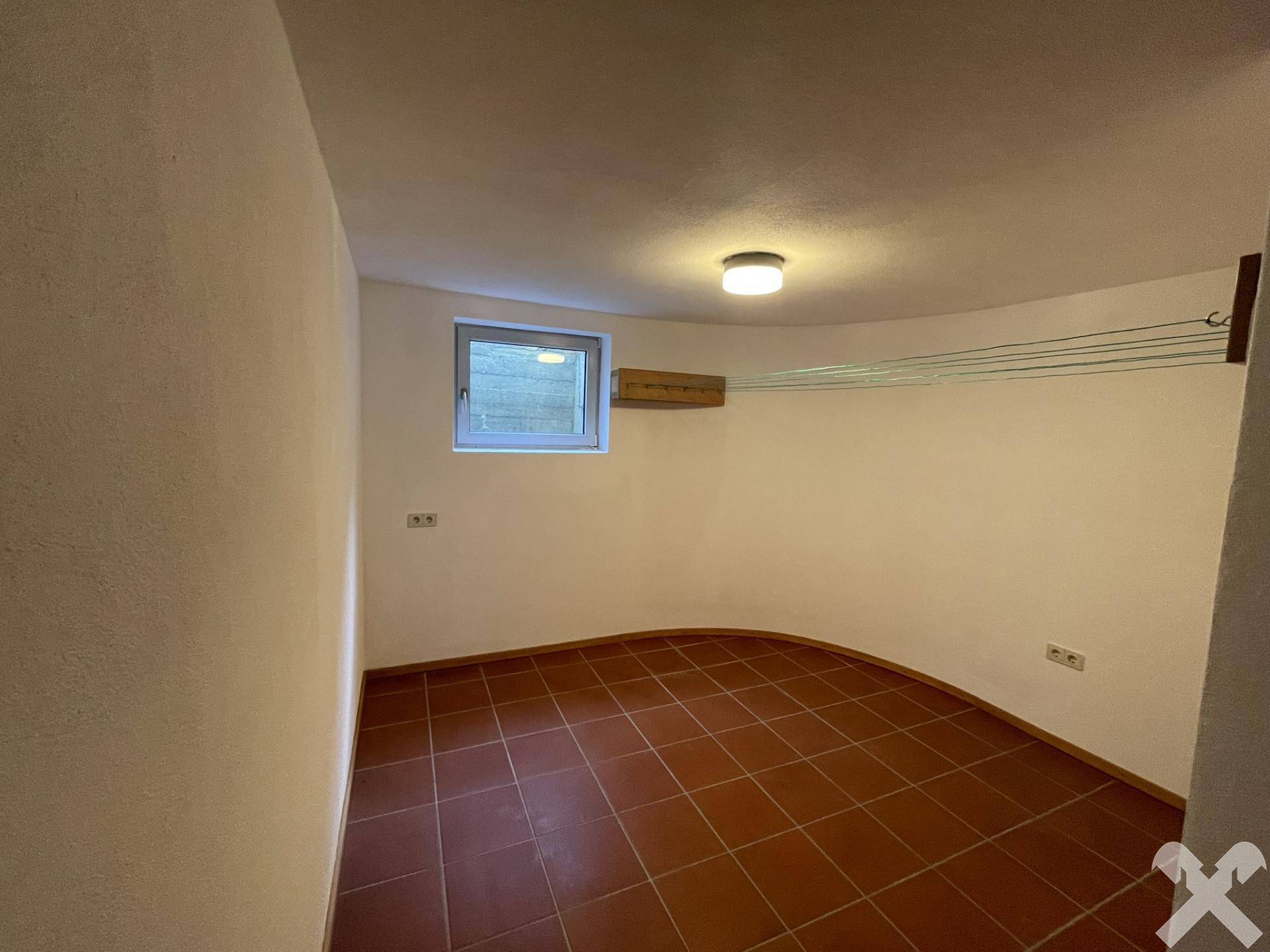 Praktischer Hauswirtschaftsraum im Keller mit Fenster und Wäscheleinen zum Trocknen.
