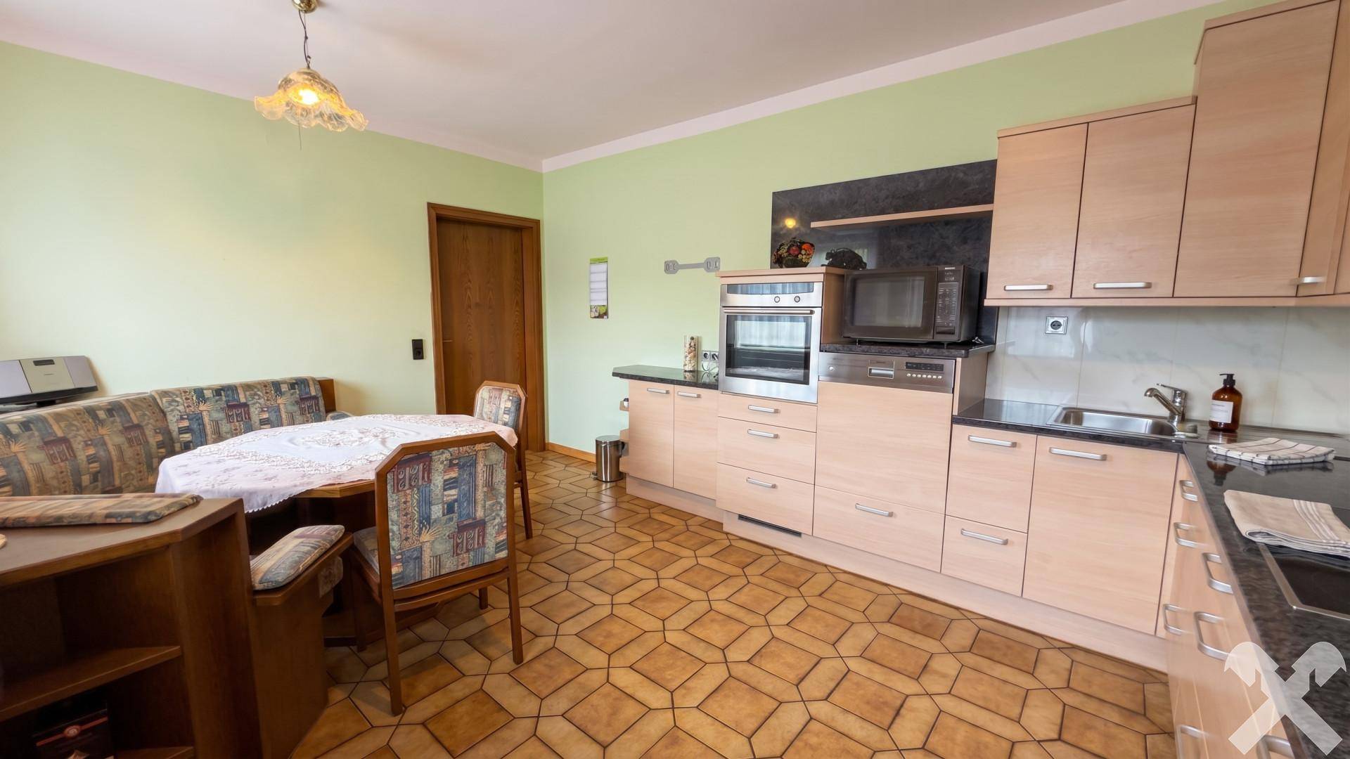 Gemütliche Wohnküche mit heller Holzfront, Essbereich und traditionellen Fliesen.