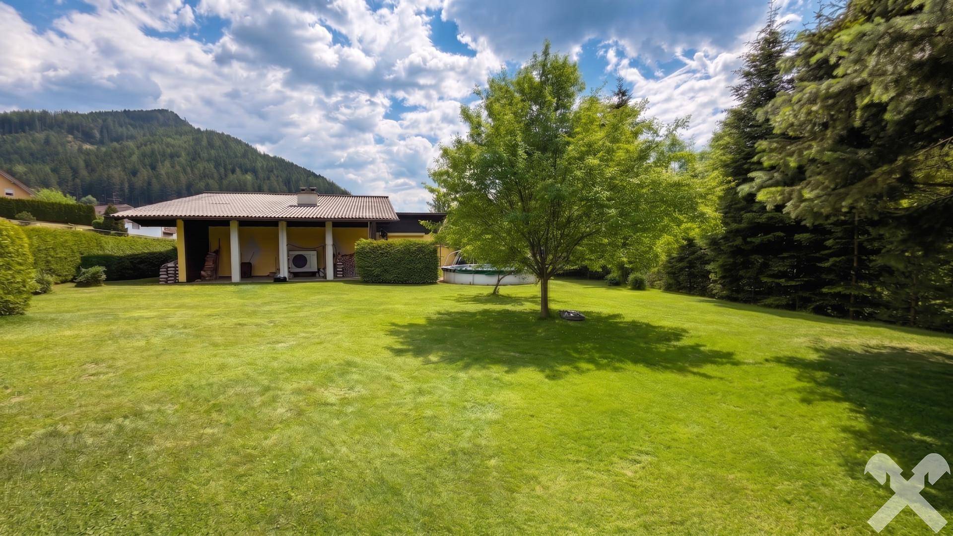 Weitläufiger Garten mit gepflegtem Rasen, Bäumen und idyllischem Bergblick.