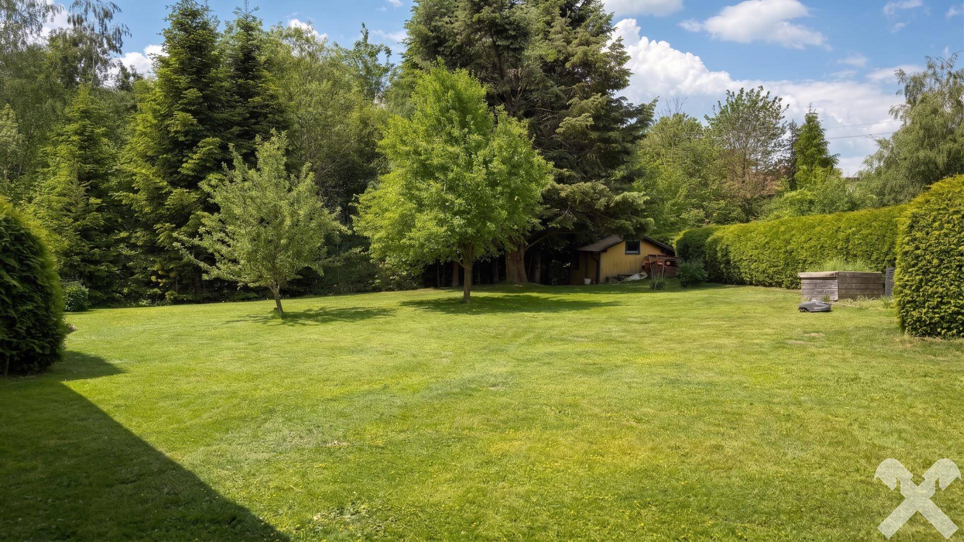 Große Rasenfläche im Garten mit altem Baumbestand, Hecke und einem kleinen Gartenhaus.