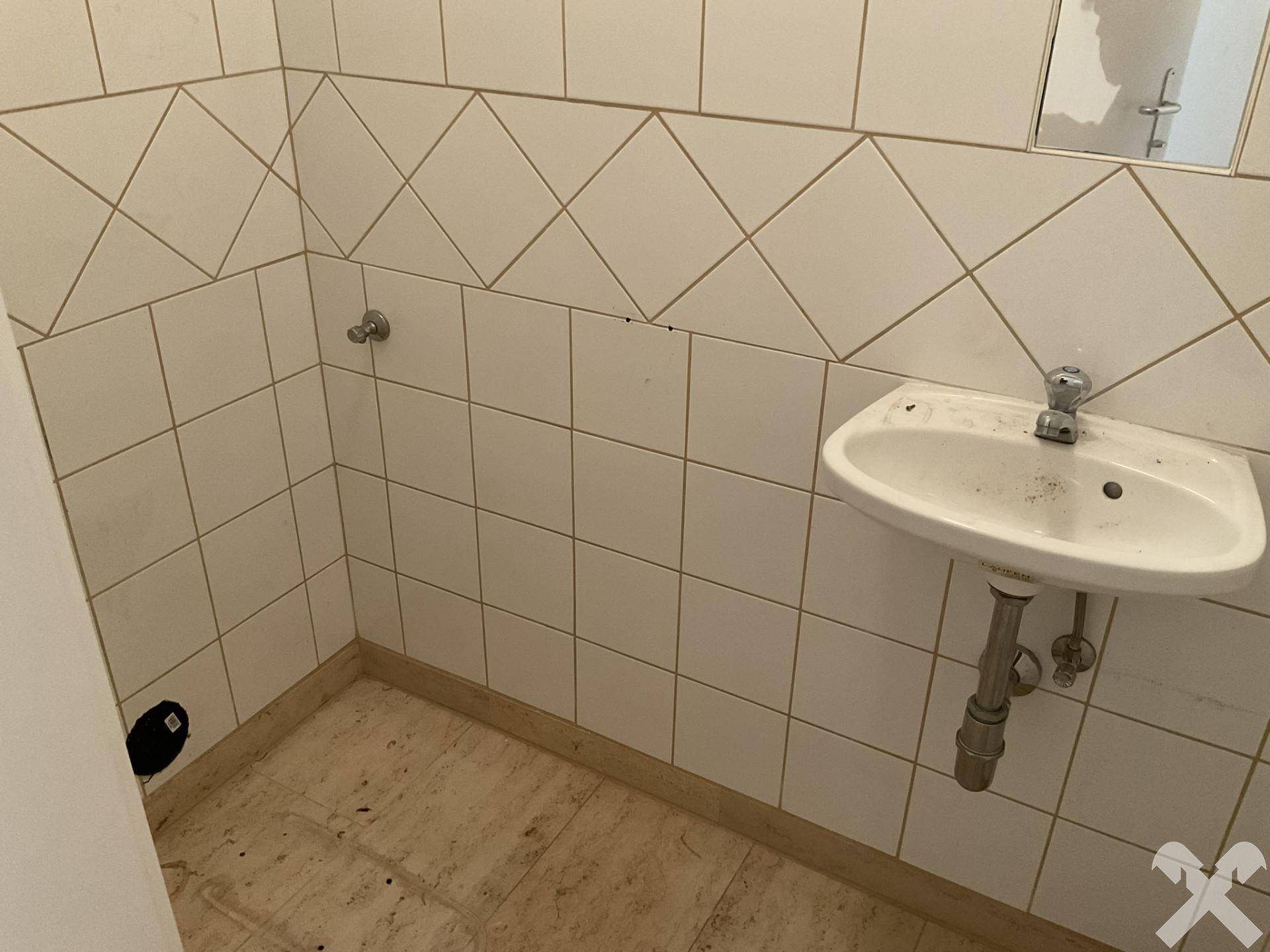 Kleines Gäste-WC mit weiß gefliesten Wänden und einem einzelnen Waschbecken.
