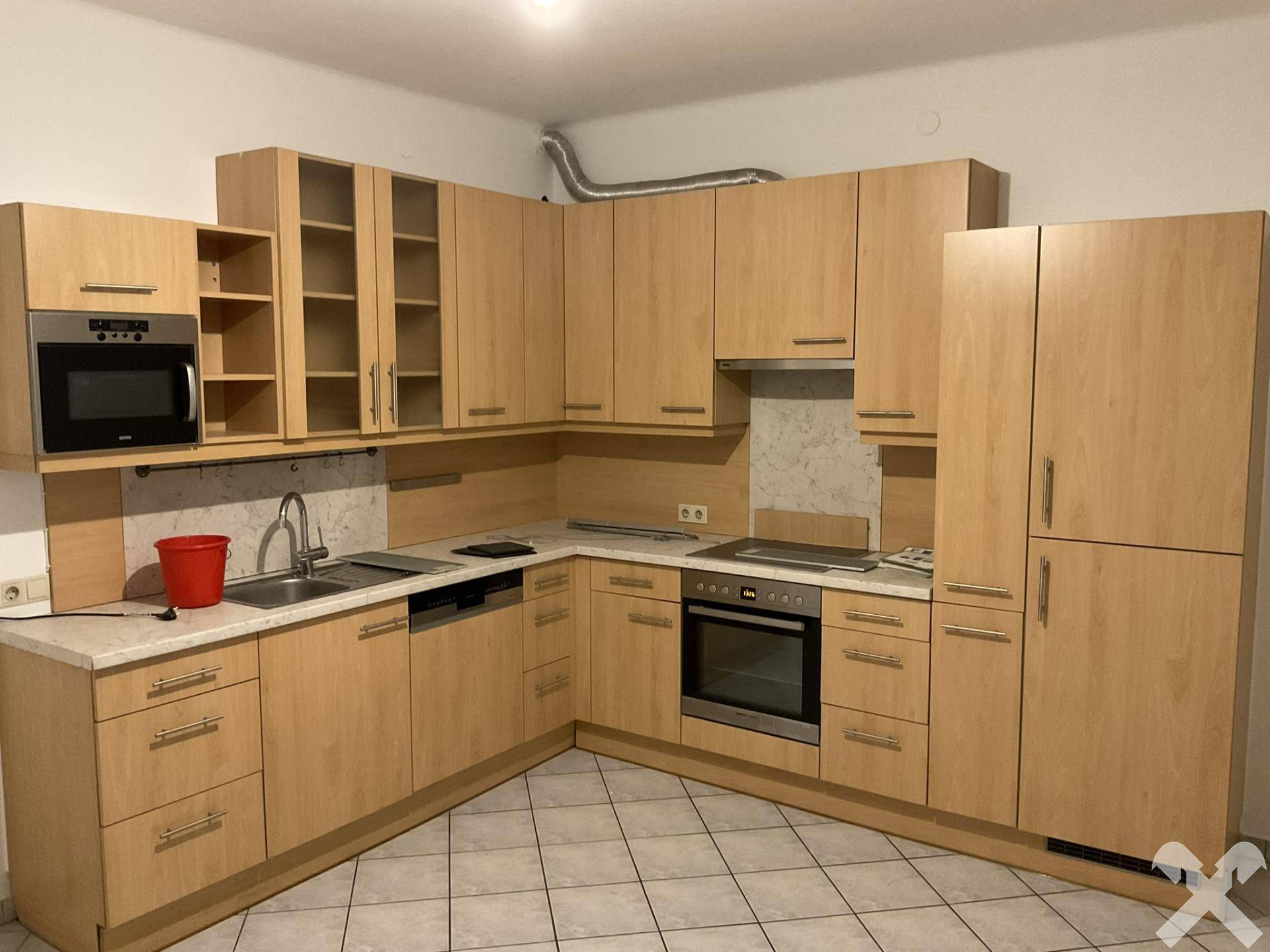 Einbauküche in Holzoptik mit integrierten Geräten und Fliesenboden.