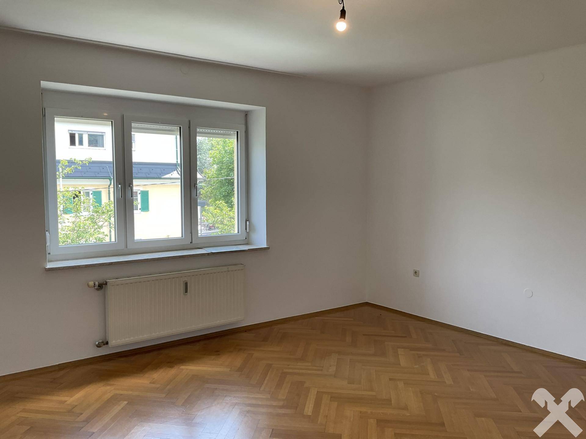 Geräumiges Zimmer mit Fischgrätparkett und großen Fenstern für viel Tageslicht.