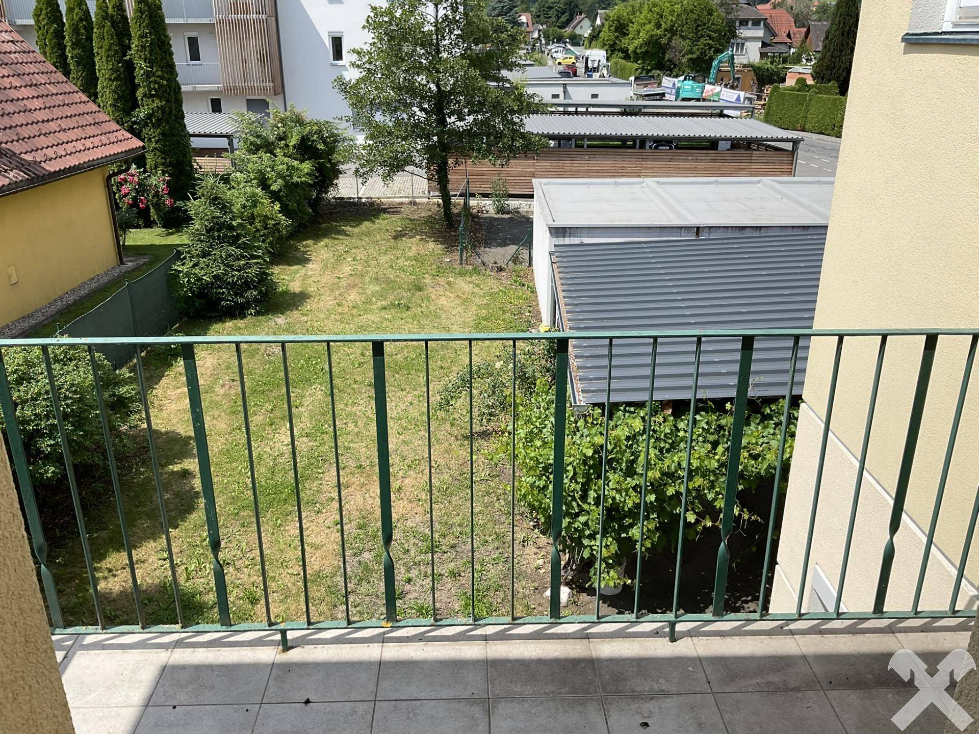 Kleiner Balkon mit Fliesenboden und Blick auf den Gartenbereich.