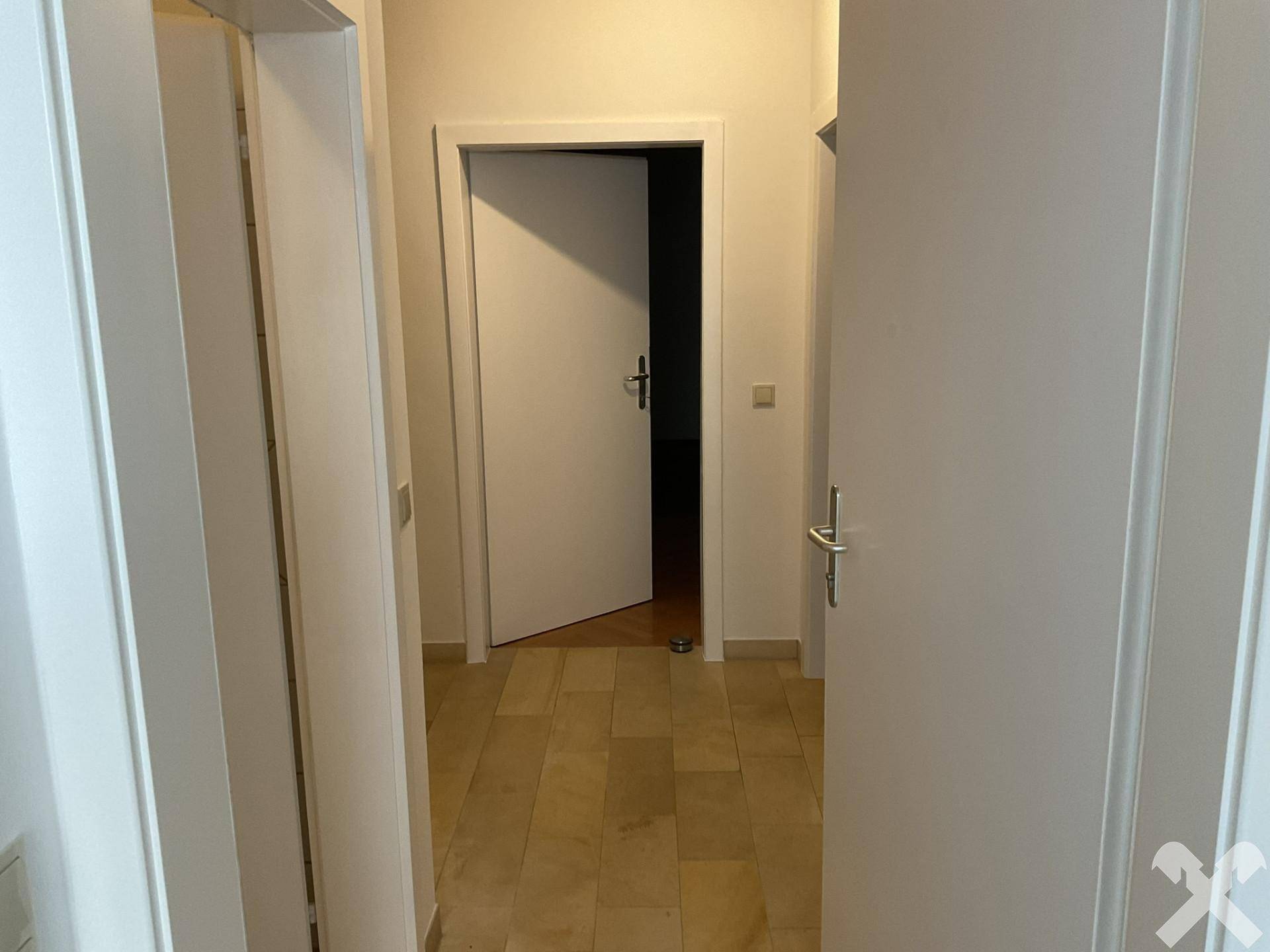 Heller Eingangsbereich mit Fliesenboden und weißen Türen zu den Zimmern.