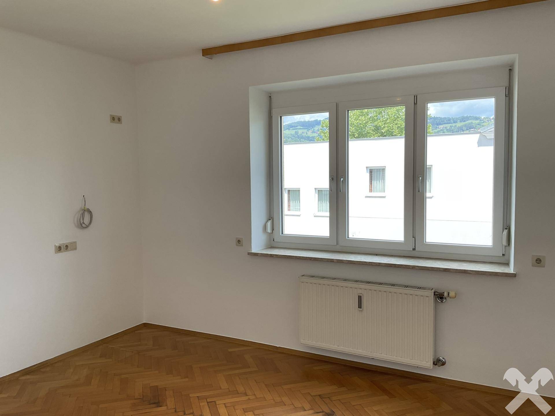 Helles Zimmer mit Parkettboden und weitem Blick auf die umliegende Landschaft.