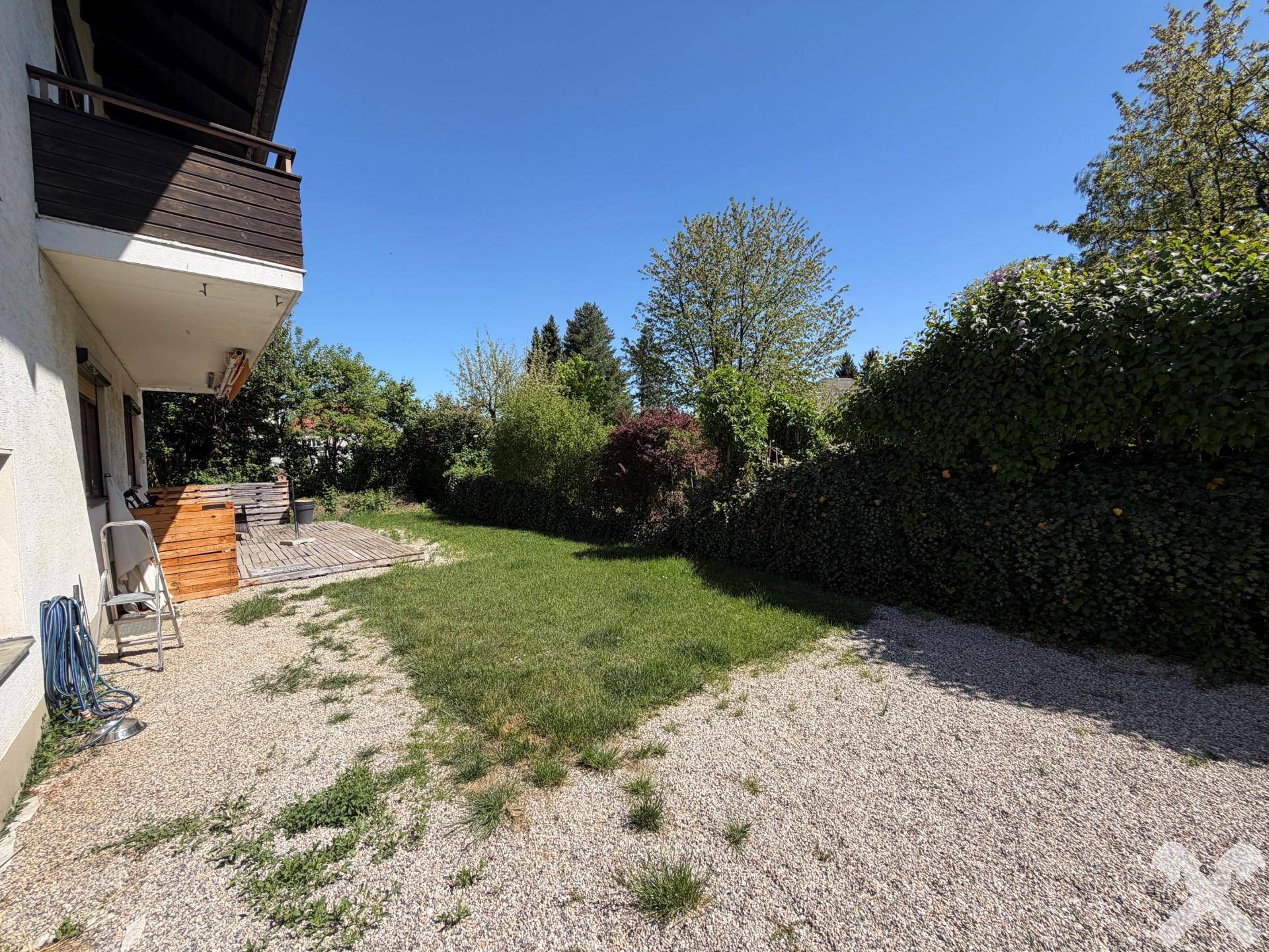 Großer Gartenbereich mit Rasenfläche, Kiesweg und üppiger Bepflanzung hinter dem Haus.