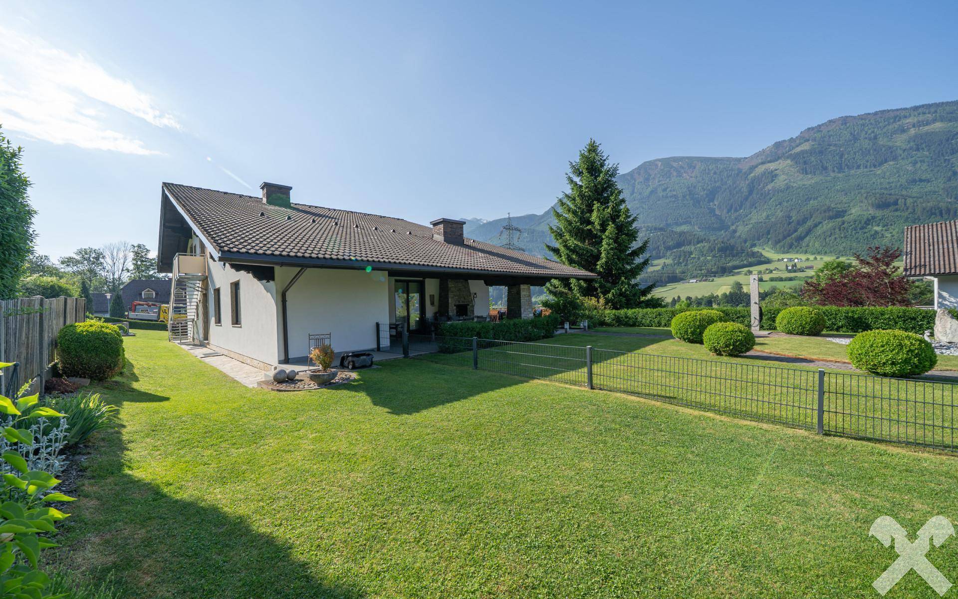 Weitläufiger, gepflegter Garten mit Rasenfläche und Blick auf die umliegende Berglandschaft.