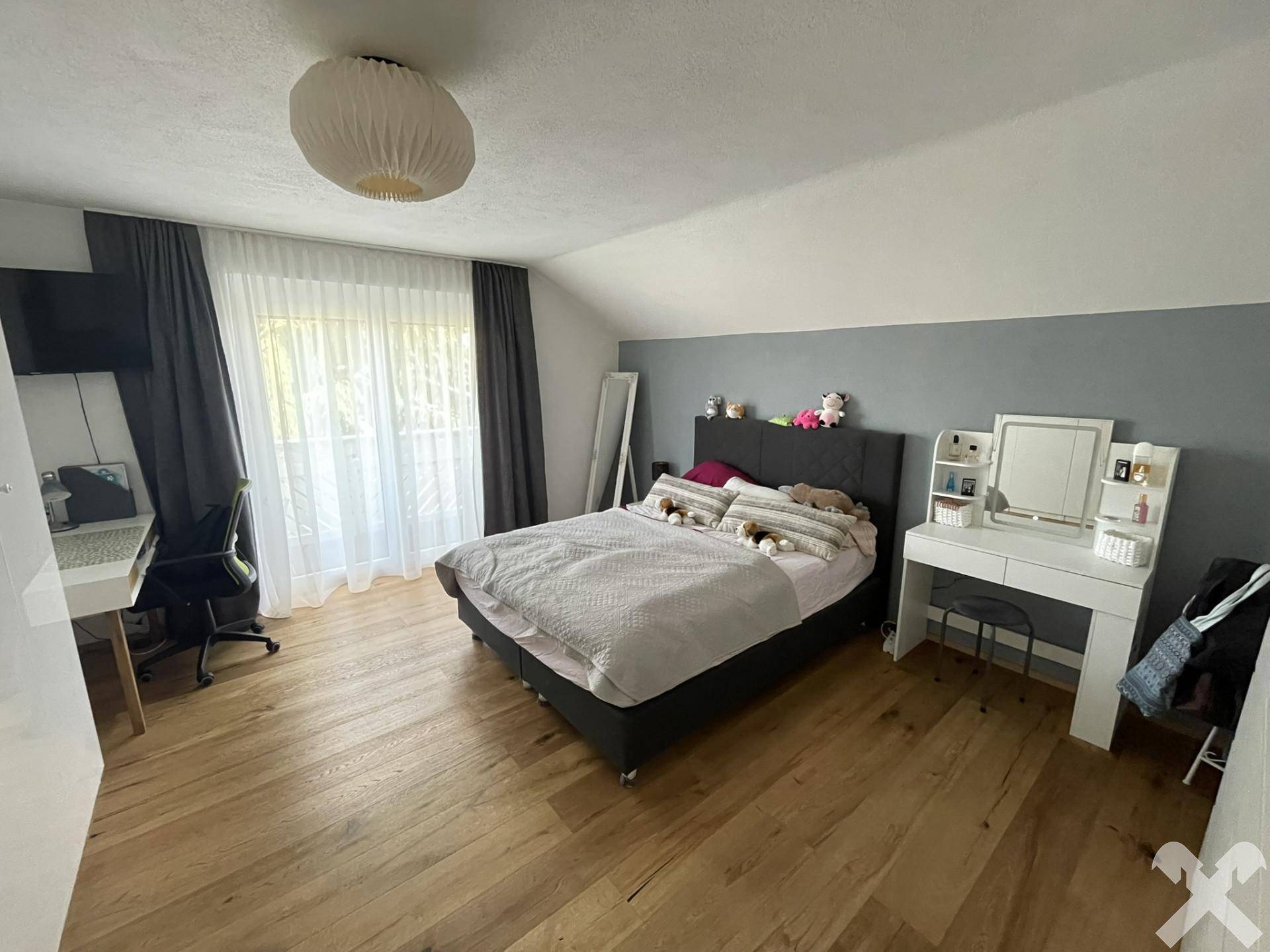 Helles Schlafzimmer mit Holzboden, Doppelbett und Schminktisch, mit Zugang zum Balkon.