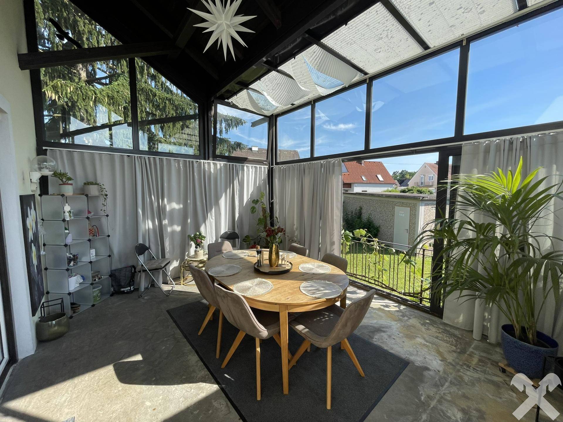 Heller Wintergarten als Essbereich mit großem Esstisch und Blick in den Garten.