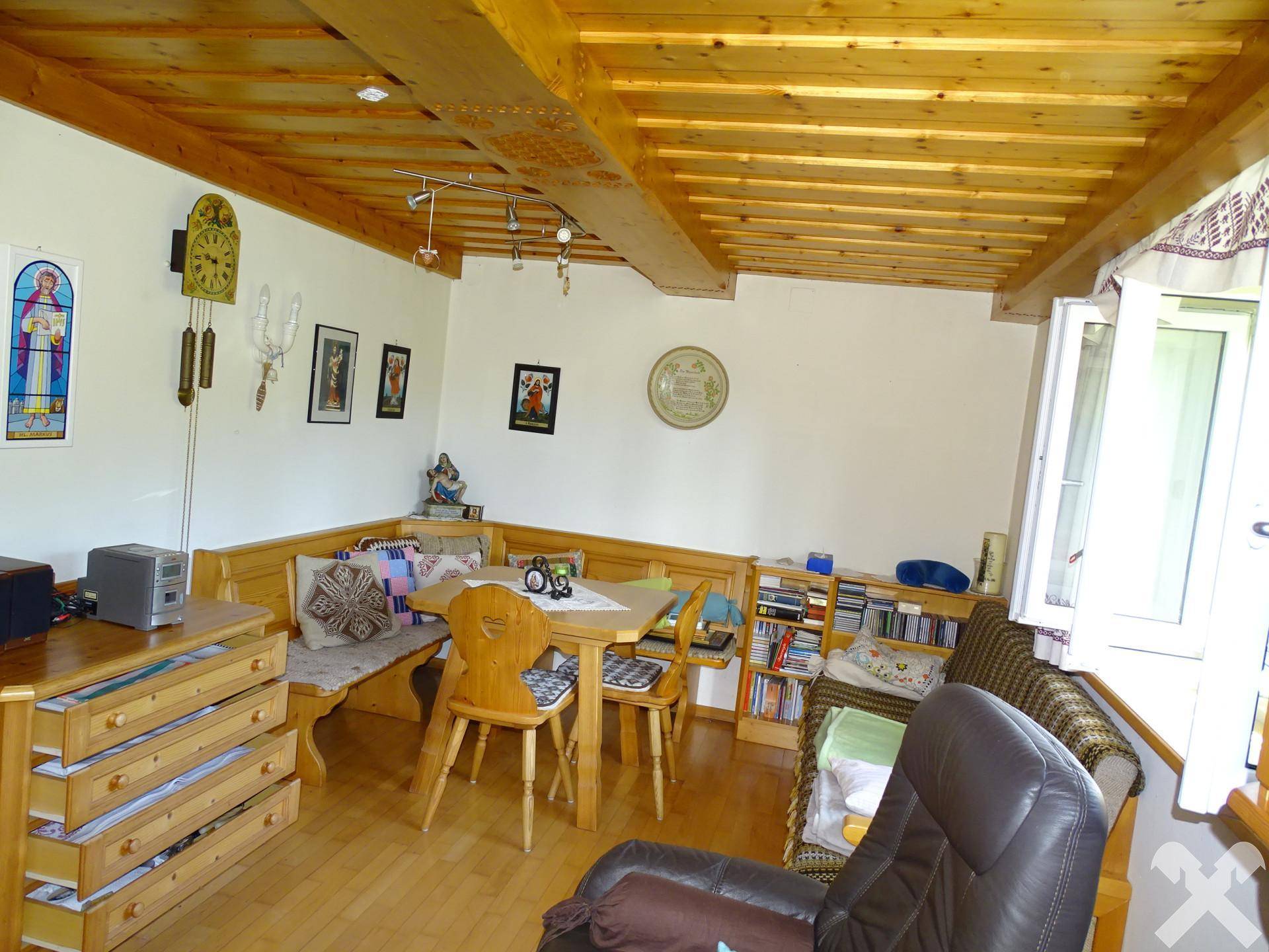 Gemütliches Wohnzimmer mit Holzbalkendecke, traditionellen Holzmöbeln und ländlicher Dekoration.