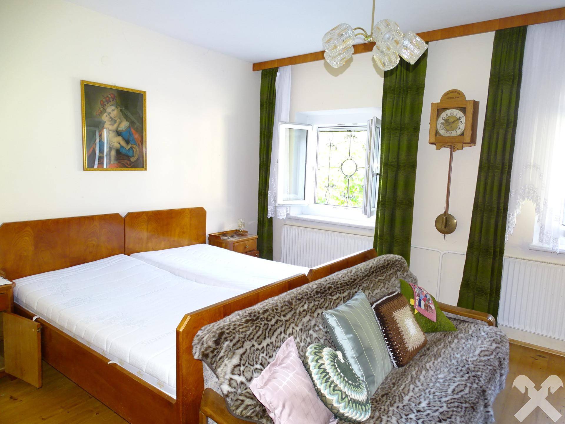 Gemütliches Schlafzimmer mit Doppelbett, Sofa und traditionellen Wanddekorationen, bietet eine warme Atmosphäre.