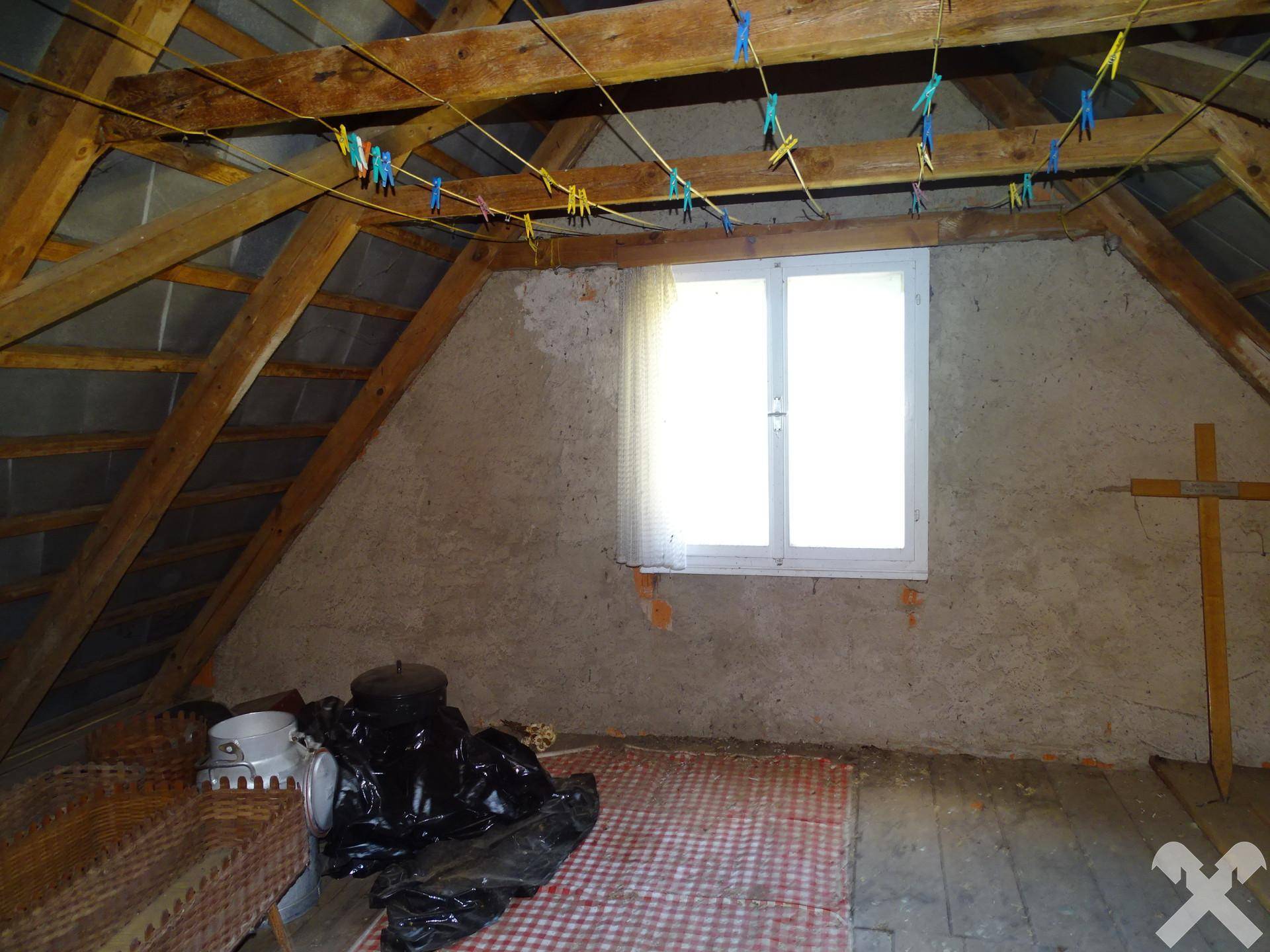 Dachbodenraum mit sichtbaren Holzbalken, Fenster und schrägen Decken, bietet Ausbaupotenzial.