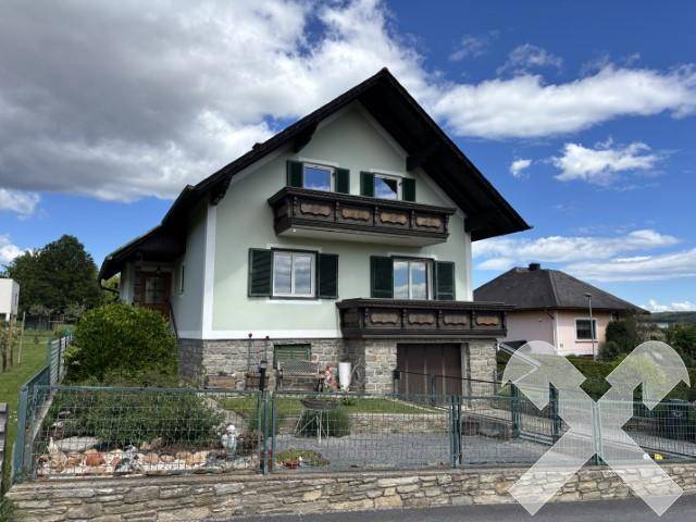 Ansicht des Hauses von der Straße mit gepflegtem Vorgarten und traditionellen Balkonen.