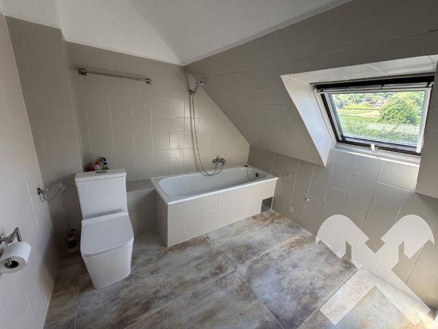 Badezimmer im Dachgeschoss mit Badewanne, Toilette und Dachfenster für natürliches Licht.
