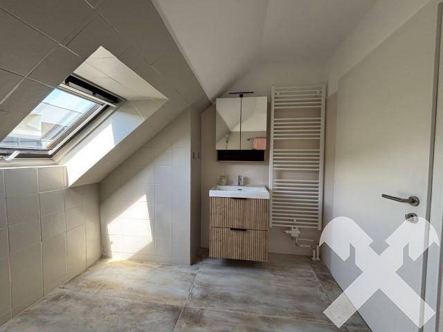 Modernes Badezimmer im Dachgeschoss mit Waschtisch, Spiegelschrank und Dachfenster.