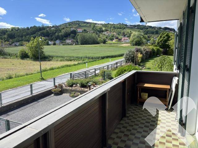 Balkon mit Fliesenboden und weitem Blick über Felder und grüne Hügel.