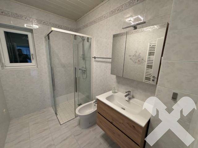 Modernes Badezimmer mit Duschkabine, Waschtisch, Bidet und beheiztem Handtuchhalter.