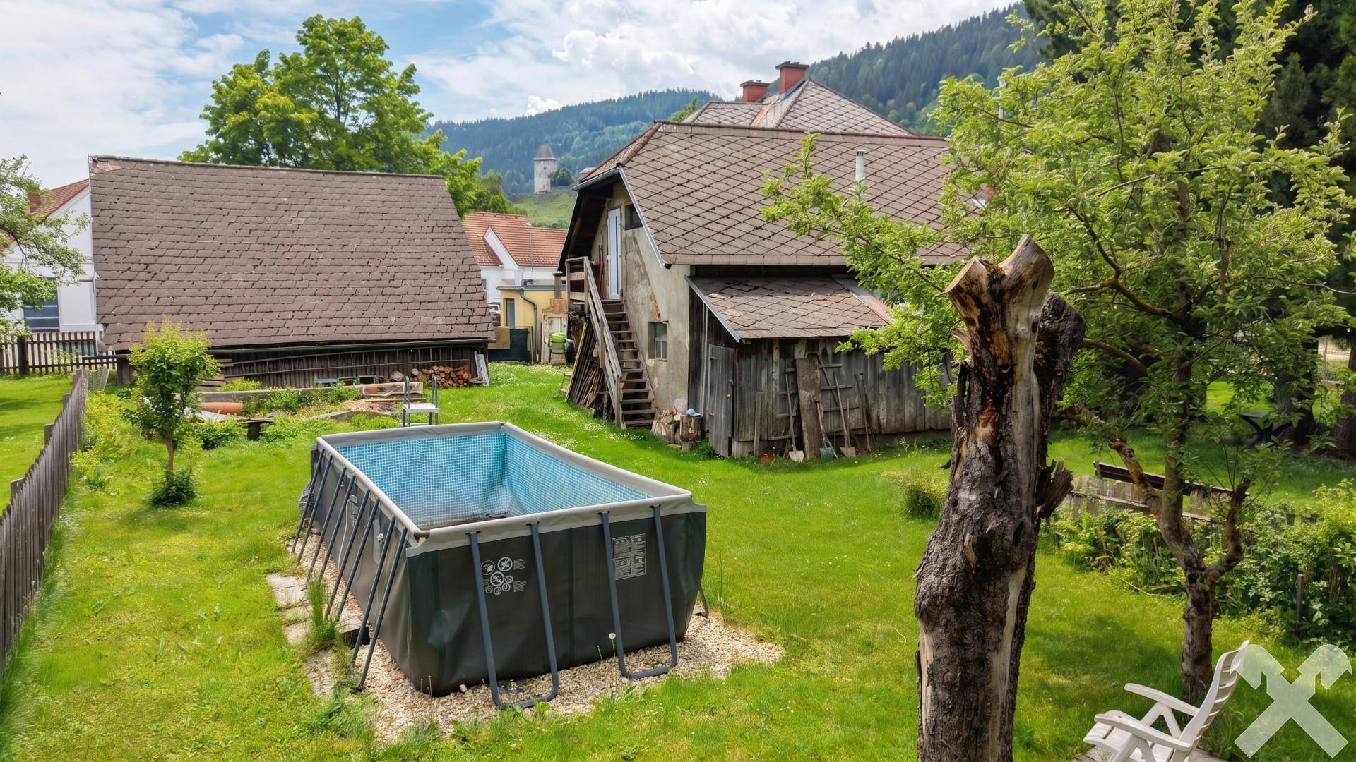 Großer Gartenbereich mit einem Aufstellpool, alten Bäumen und einem Holzschuppen im Hintergrund.